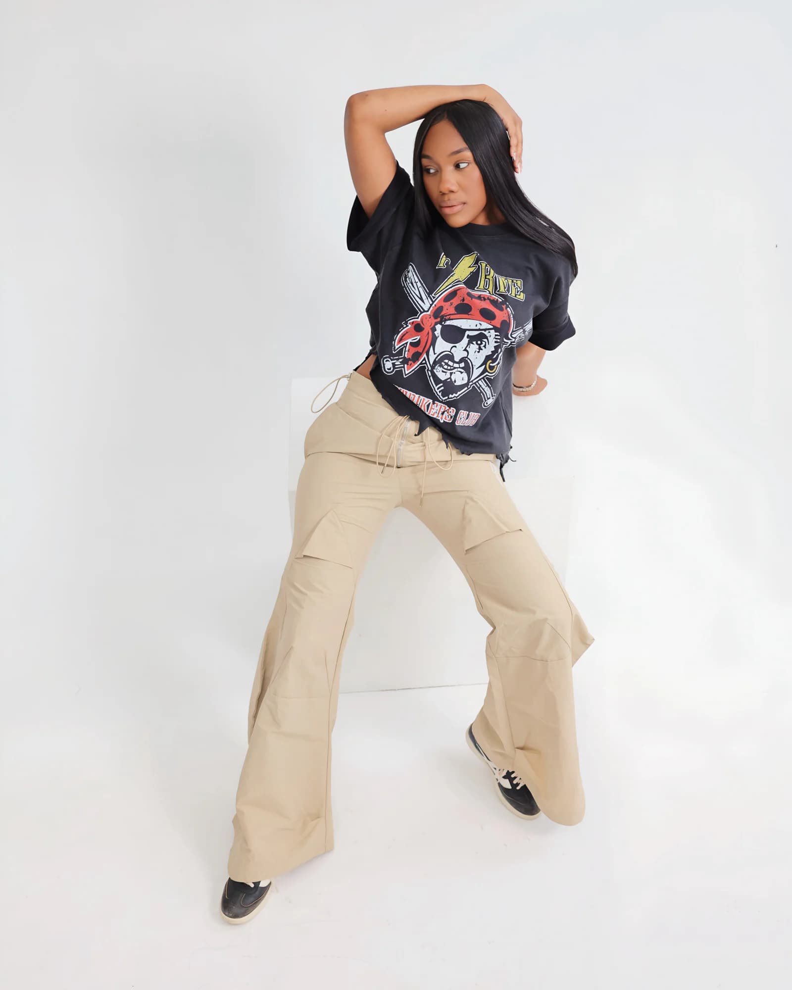 Model styling the black PSRVE Striker Tee in a seated studio pose